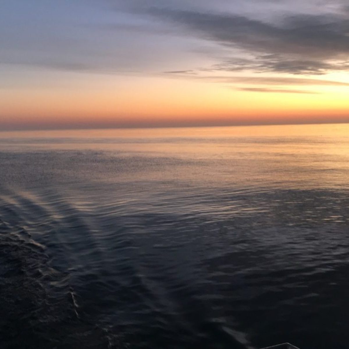 Sunset over ocean with a flag waving on the side.