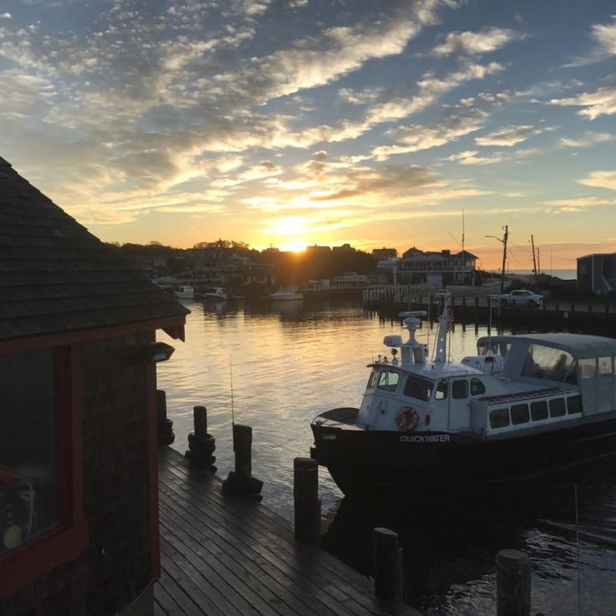 Boat docked at pier during sunset with buildings in the background.