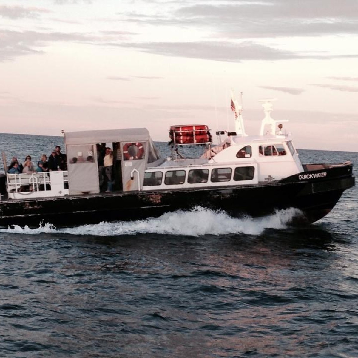 Small boat with passengers traveling on calm ocean waters.