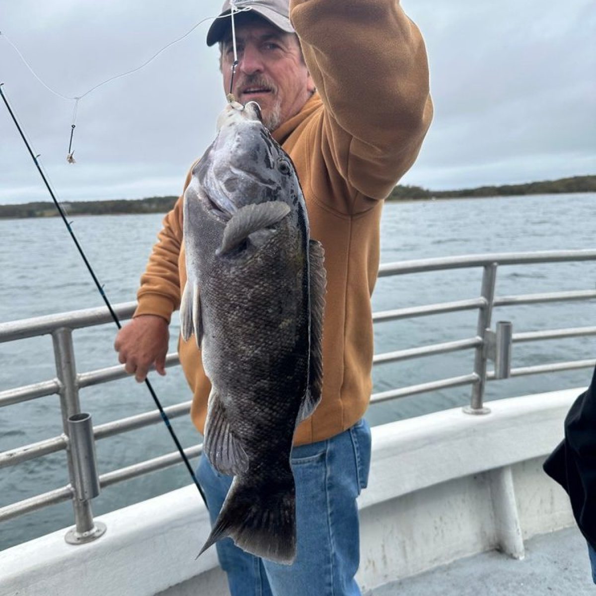 Man on a boat holding a large fish he caught.