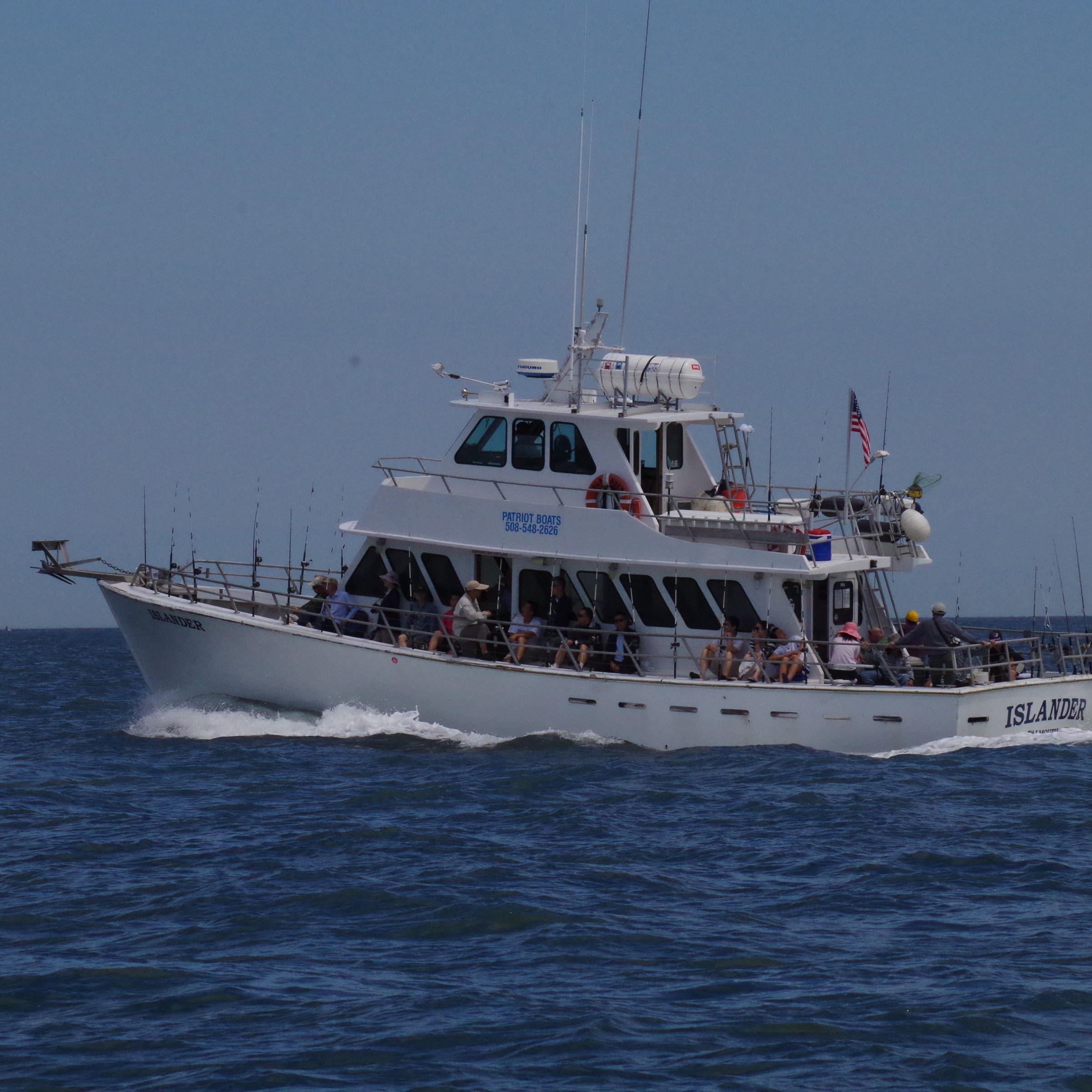 White fishing boat with people on deck in open sea