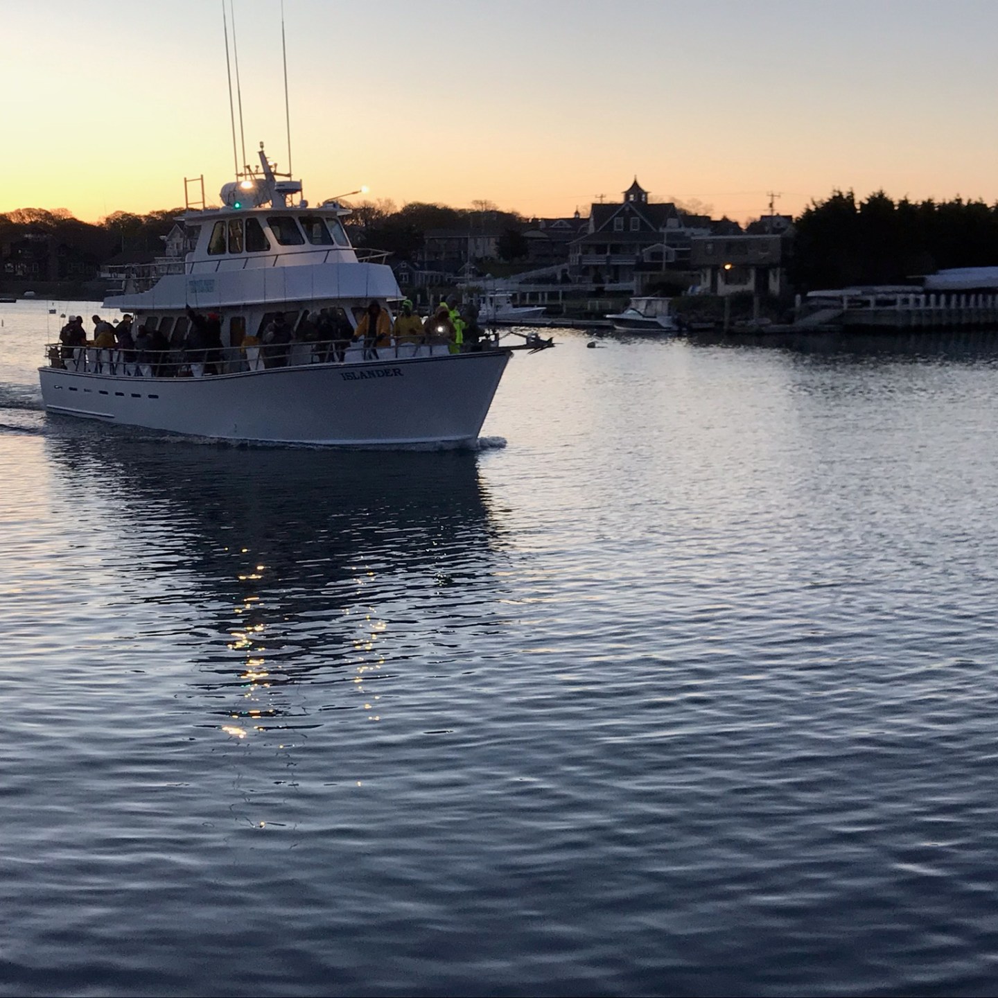 Boat on water at sunset with silhouetted landscape in background.