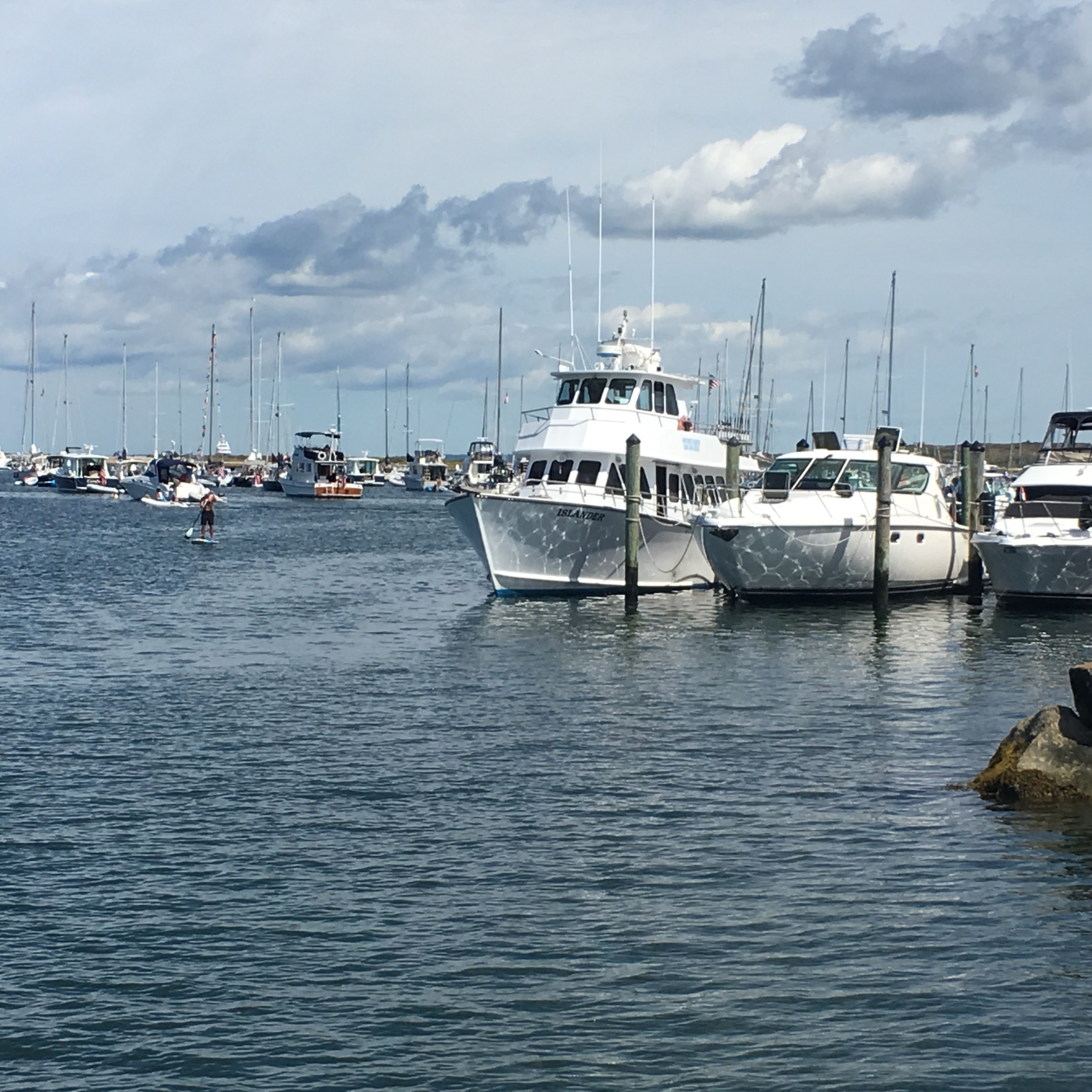 Boats docked in a harbor under a partly cloudy sky.