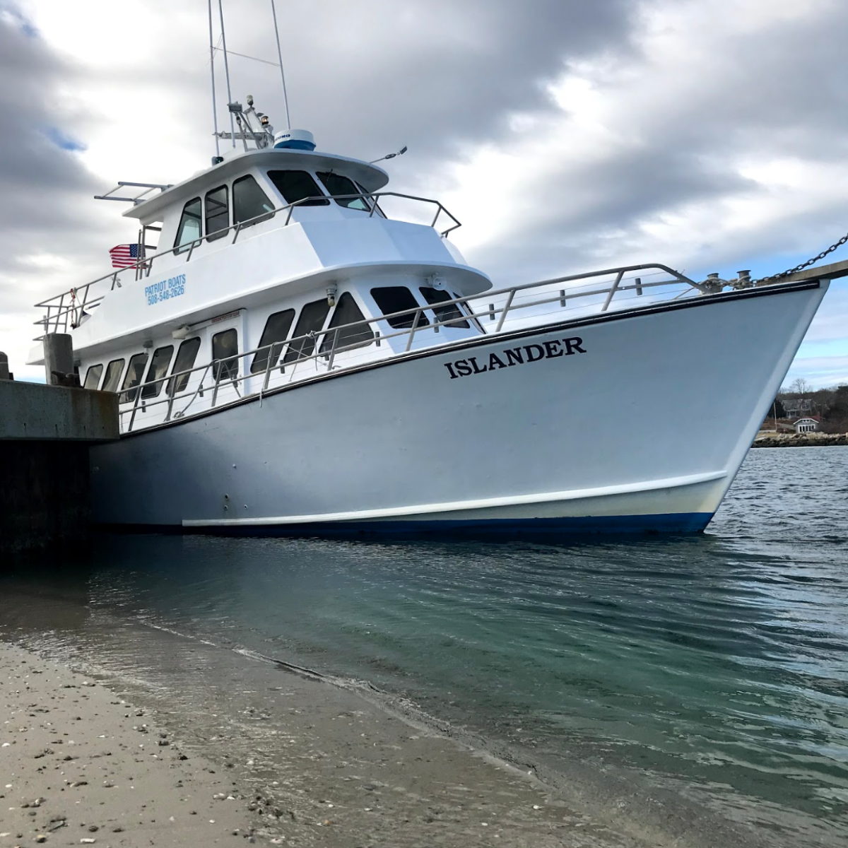 White boat named Islander docked by a pier on a cloudy day.