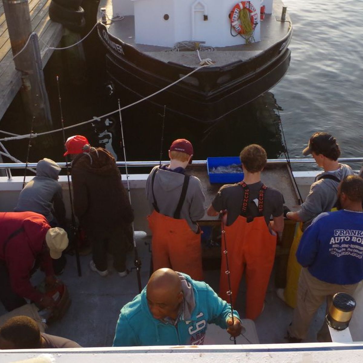People fishing on a boat docked at a pier.