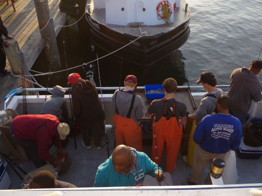 People fishing on a boat docked at a pier.