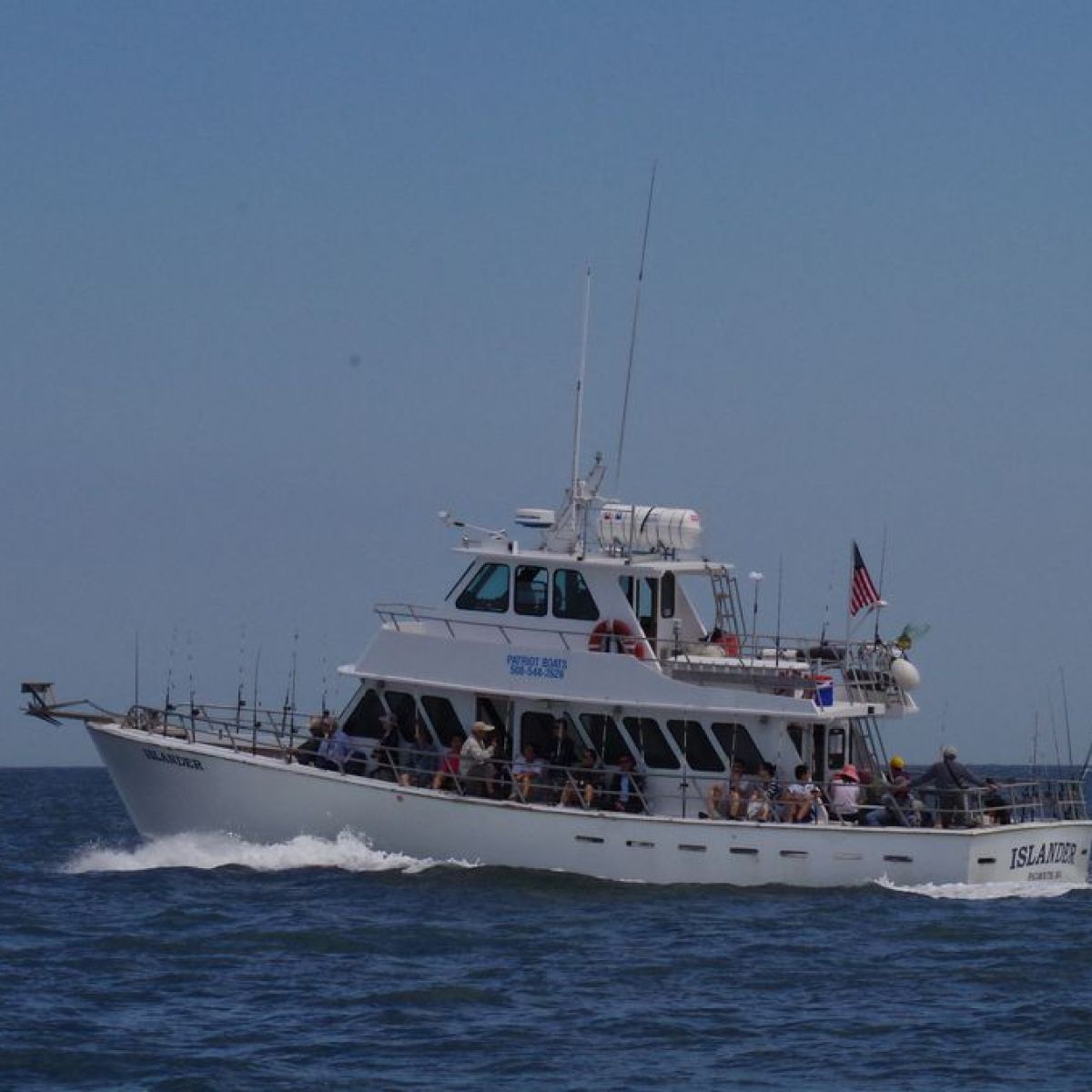 White passenger boat sailing on the ocean under a clear sky.