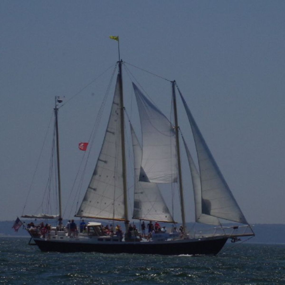 Sailboat with two sails on open water under clear sky.