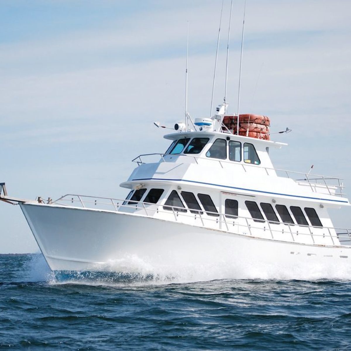 White yacht cruising on open blue water under a clear sky.