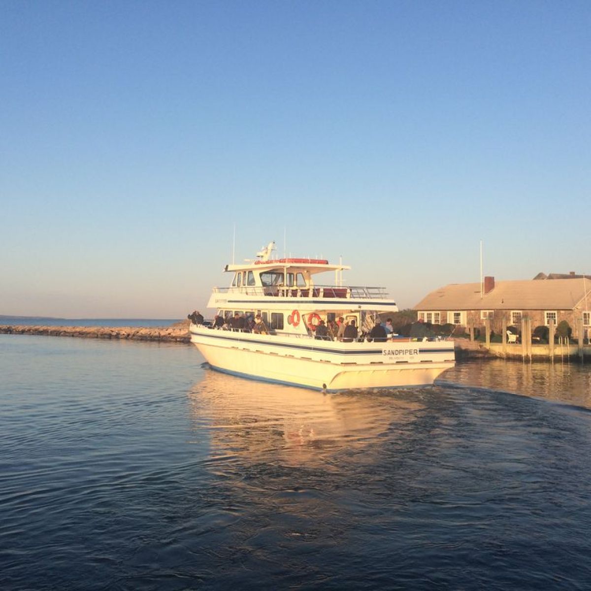 A small ferry boat near a dock under a clear blue sky.