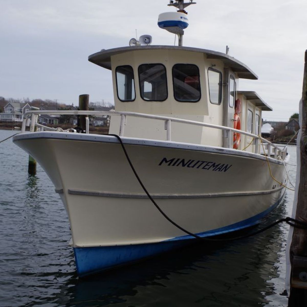 Small fishing boat named Minuteman docked at a harbor.