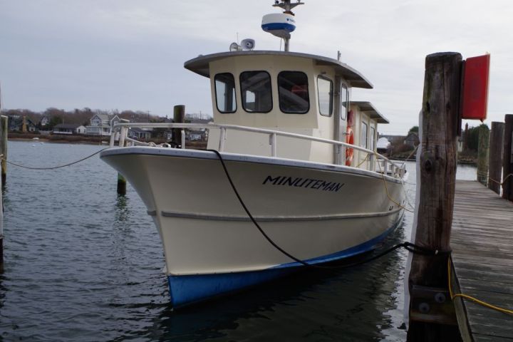 Small fishing boat named Minuteman docked at a harbor.