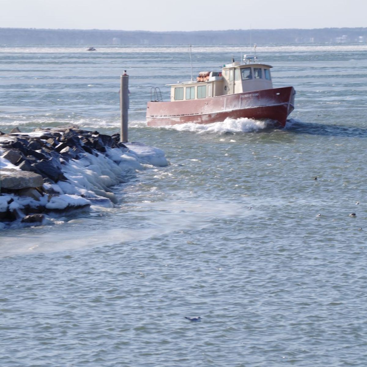 A boat navigating icy waters near a rocky coastline.
