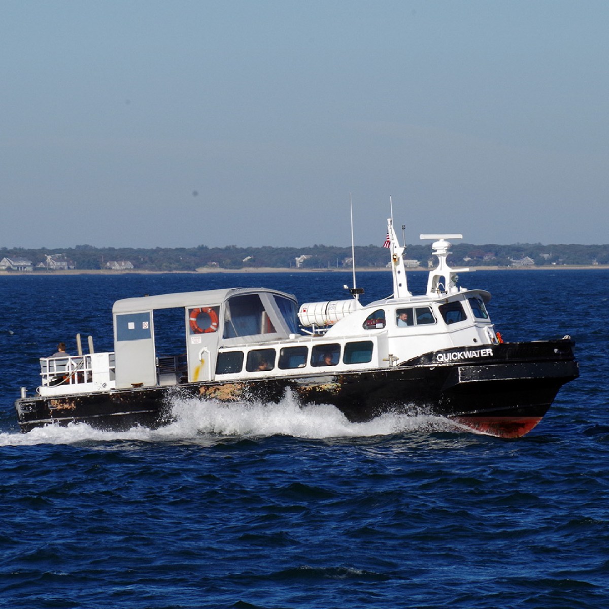 A black and white boat named 'Quickwater' cruising on a blue sea.